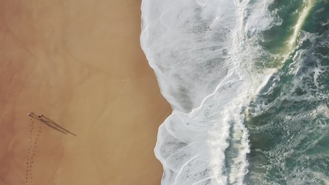 Lonely person walks along the seashore, while massive tides washing the coastline. Drone footage of stunning natural beauty on the banks of the Atlantic Ocean. High quality 4k footage
