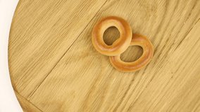 Small dry bages on a wooden board on a kitchen, wheat food concept video, rotating composition