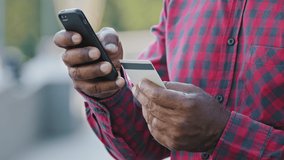 Crop closeup of African American man shopping online on cellphone pay with credit card. Biracial male buyer client place order make secure payment on smartphone, buy purchase on internet outdoors - Powered by Shutterstock - Get 15% off with code: PIKWIZARD15