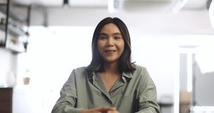 Cute and young Asian businesswoman joining video call session. Business woman shows hand greeting say hello to audience and start video talk virtual training. Work at home, new normal concept.