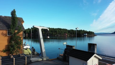 Electrical high voltage ferry charging tower - Aerial approaching and passing charger - Cables and plug hanging down ready for use - Early sunny day morning at Utbjoa Norway