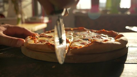 Close up macro filming of pizza pie slicing into pieces. Shots of Italian food chef cook carving up pizza with knife before serving dish on table. Professional baker cuisine, pastry foodstuff on plate