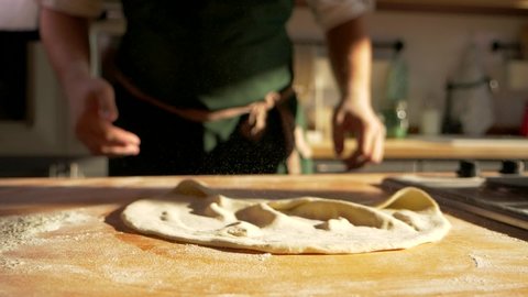 Close up macro shots of Italian bakery food restaurant kitchen. Chef cook knead future piece of pizza, forms the dough, demonstration of pastry stretching. Pizza form falling. Professional cuisine.