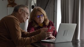 two elderly people surfing internet on laptop computer at home. 4K video 