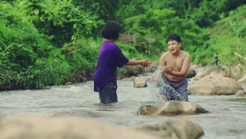 Children playing with friend in the river at countryside,Boys and girls smiling and happiness playing water at countryside in Thailand.