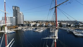 Three-masted sailing ship in harbor, on the background of a modern port city and marina, aerial view. Tall ship moored in marina on a Baltic Sea. Drone view of beautiful sailing ship in sunny day - Powered by Shutterstock - Get 15% off with code: PIKWIZARD15