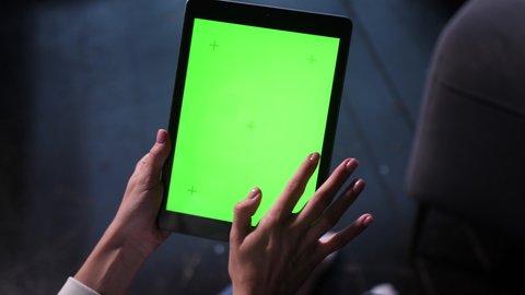 Closeup shots of green screen on iPad. Female person holds in hands portable tablet computer with moving green motion tracking points. Touching device screens surface with fingers, swiping and zooming