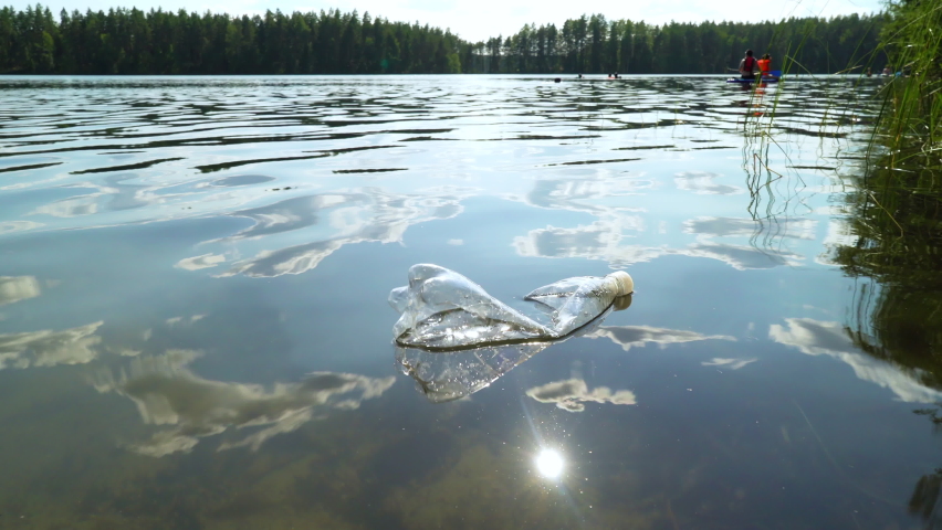 Plastic trash in nature. Used bottle floating on water. Plastic garbage pollution forest lake. World's plastic pollution crisis concept. | Shutterstock HD Video #1079526221