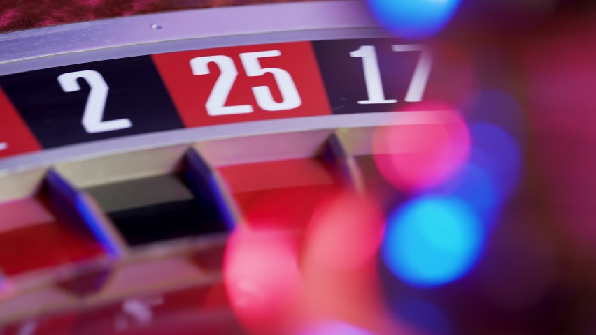 A casino roulette wheel with a white ball on green 0. Casino game table, close up numbers. Part of the roulette wheel runs in slow motion. Selective focus, bokeh. - Powered by Shutterstock - Get 15% off with code: PIKWIZARD15