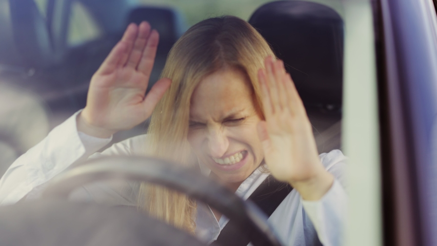 Angry mature woman sitting in car and pounding with hands on steering wheel. Business lady driving vehicle with negative emotions. Problems, traffic, hurry concept.