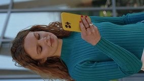 Beautiful young lady with curly blond hair using modern smartphone while resting outdoors. Concept of free time and social networks. Horizontal video.