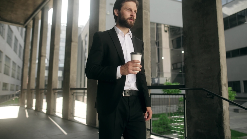 Attractive young handsome man with coffee cup walking down stairs. Sucessful businessman.