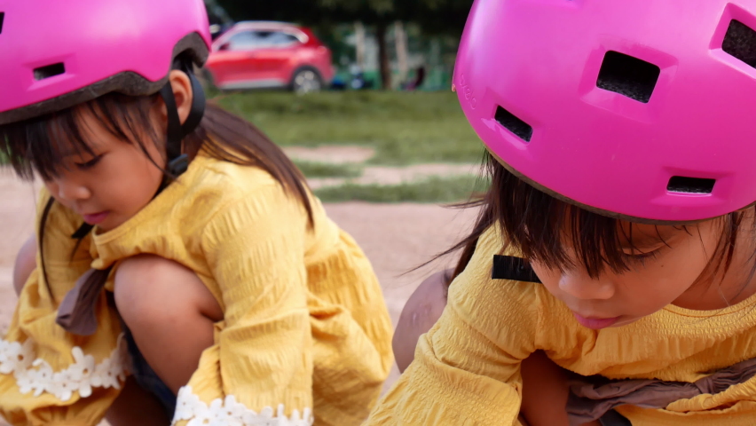 Two cute little sisters in helmets are playing with sand in park on a sunny summer day, taking a break after cycling practice. develop imagination and exploration.