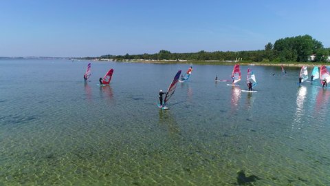 Windsurfing and windsurfers at a calm sea, aerial view. Summer vacation at surfers village in a sunny day. Lot of windsurfers from a windsurfing club or school.