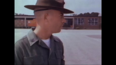 1960s: Drill sergeants inspect recruits and their guns. Recruit scrubs rifle with tooth brush. Recruits look at pictures and shine their shoes in beds. Recruits line up at bunks in barracks.