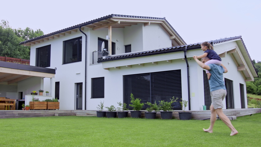 Father with daughters playing outdoors in the backyard, running.