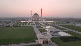 The Sharjah Mosque, is the largest mosque in the Emirate of Sharjah, the United Arab Emirates characterized by symmetry and perfection of Islamic architecture aerial footage at sunset