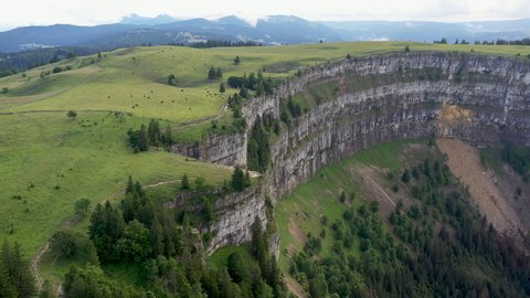 Descending drone shot of Creux du Van in Switzerland, located at the border of the cantons of Neuenburg and Vaud