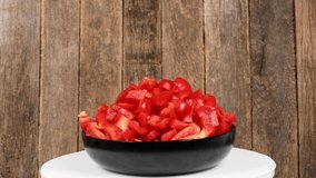 Plate of Slicing sweet peppers on wooden background. Loop motion. Side view. Rotation 360. 4K UHD video footage 3840X2160.