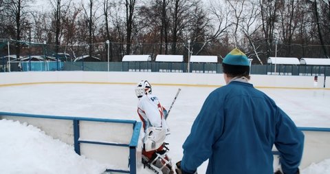 YAROSLAVL, RUSSIA - JANUARY 29 2015: the goalkeeper comes to ice. Young teenagers play hockey in the yard. They drive the puck, hit shootouts, skate. Two brothers and winter fun on School ice rink