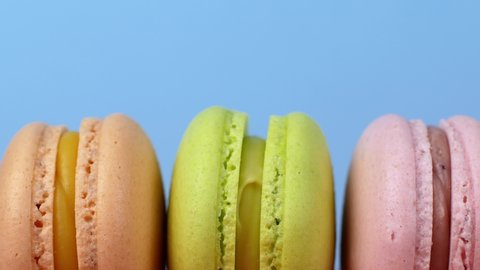 Multicolor Macarons, French macaroon, sweet tasty desserts. Isolated on a blue background.