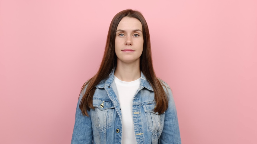 Fun shy ashamed caucasian female 20s years old look camera spreading hands say oops ouch oh omg i am so sorry, wears blue denim jacket, posing isolated on pastel pink color background in studio Royalty-Free Stock Footage #1079556821