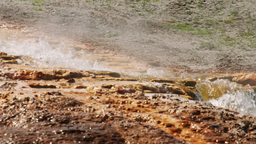 Hot springs in world famous Yellowstone National Park 4K. Slow motion hot water stream flowing down from volcanic geyser basin by iron and cooper mineral elements reach surface in vibrant orange color