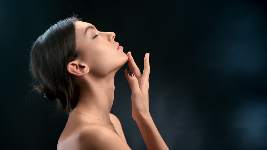 Adorable fashion model touching chin smooth skin body care posing isolated on black gradient studio background. Beautiful lady stroking neck fresh healthy skincare beauty salon spa plastic surgery Royalty-Free Stock Footage #1079558897