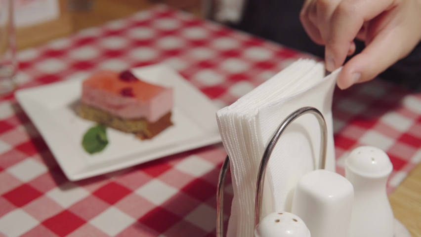 A person uses paper napkins while eating. A man's hand brings a napkin to him and takes it from napkin holder. Napkins in the italian restaurant on the table. high quality footage. | Shutterstock HD Video #1079561969