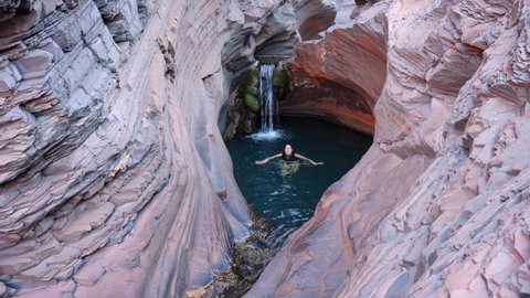 KARIJINI, AUSTRALIA - MAY, 26, 2021: a young female tourist swimming in the spa pool at karijini national park of western australia