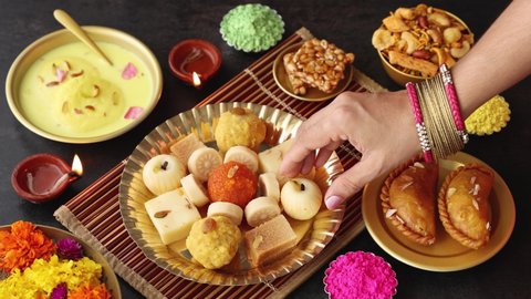 Women hand taking mix of Indian sweet food specially made for festivals of India like Diwali Gujiya peda barfi Indian sweet dessert mithai festival Dussehra Holi Ganesh Chaturthi Ram Navami Durga