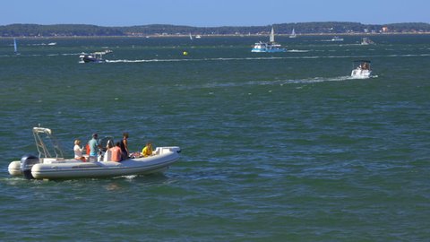 Arcachon, France - August 2021 : tourists on board a motor inflatable boat crossing the screen navigating on the Arcachon Bay