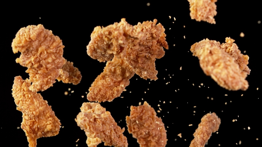 Super slow motion of flying fried chicken pieces on black background. Filmed on high speed cinema camera, 1000fps. Speed ramp effect. Royalty-Free Stock Footage #1079570642