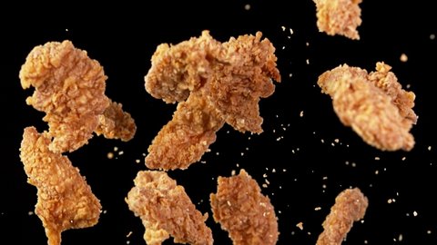 Super slow motion of flying fried chicken pieces on black background. Filmed on high speed cinema camera, 1000fps. Speed ramp effect.