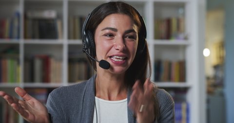 Cinematic shot of young business woman is making video conference assistance call to colleagues or customers while doing smart working in living room at home.