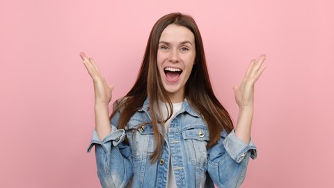 Excited jubilant overjoyed cheerful fun young brunette woman 20s years doing winner gesture celebrate clenching fists say yes, wears denim jacket, posing isolated on pink color background in studio