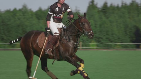 UFA RUSSIA - 05.09.2021: Match on a horse in a polo club. Two riders make a hit on a white ball on green grass. Players hit the ball a wooden stick to polo. Luxury game, slow motion.