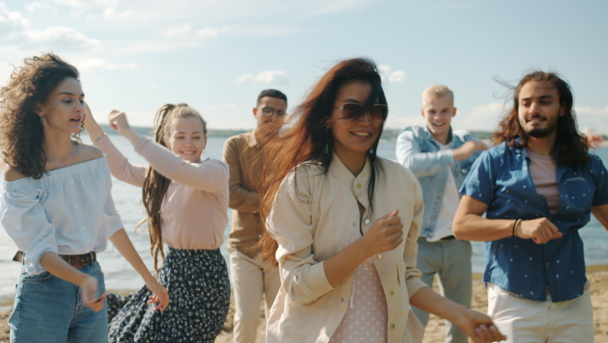 Slow motion portrait of girls and guys dancing jumping having fun on beach on summer day. Leisure time activities and positive emotions concept. - Powered by Shutterstock - Get 15% off with code: PIKWIZARD15