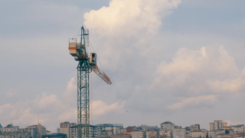 Long construction crane against the blue sky. Tower crane for lifting loads in the construction of tall buildings.
