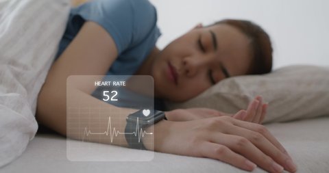 Asia woman wear smartwatch for sugar tracker, blood pressure tracking, resting sleep rate on arm IoT tech collect data app device relax body on cozy bed in future life at home.