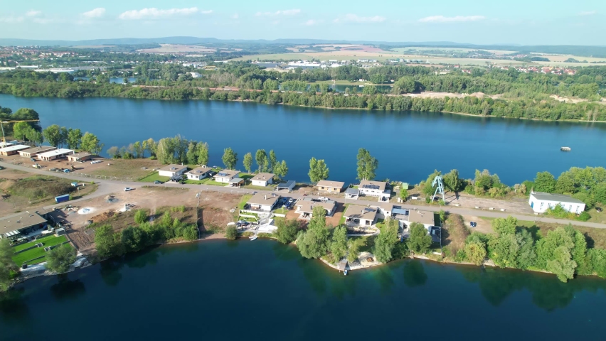 Drone shot of a beautiful quarry lake landscape with residential houses and green shores  Clear blue water lakes in Germany  Sideways moving 