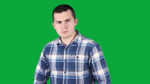 a cheeky guy in a shirt twitches at the camera on the background of a green screen
