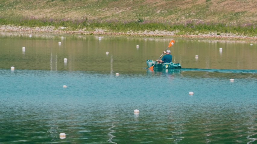 A male paddling on a kayak in 4K