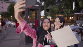 A young multi ethnic female Muslim joyfully taking selfie beside busy downtown road, with a view of skyscraper and city shops behind, non plastics bags concept, a friendship having fun memory concept