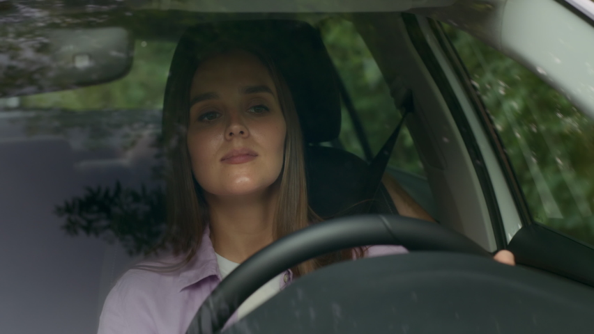 Young woman driving car and looking around at road traffic of green city. Adult girl having safety ride to job in vehicle. Concentrated female driver sitting inside and going to summer trip closeup | Shutterstock HD Video #1079607185