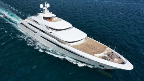 Mykonos, Cyclades  Greece - September 4 2021: Aerial drone video of beautiful modern super yacht with wooden deck cruising in high speed in Aegean deep blue sea