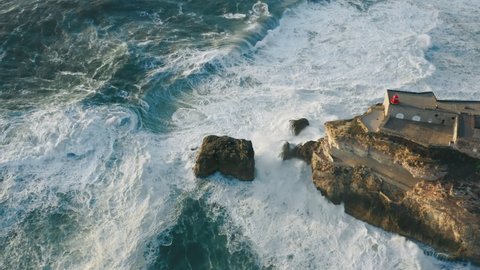 Mecca for surfers with the biggest waves in the world as seen from above. Jaw-dropping drone footage of giant rocky cliff with Farole de Nazare on top. High quality 4k footage