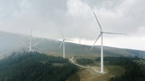 Panoramic view of windmills producing electricity. Windmill energy transformation. Wind turbines rotating by wind. Wind farm located on mountain hills on cloudy day, 4k footage