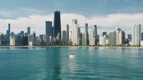 Aerial view of Chicago skyline and white sailing boat in Michigan lake blue green still waters with downtown Chicago on motion background. Water sports tourism, leisure activity, summer vacation 4K