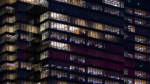Time lapse people working late night, office windows light in business center building facade. Corporate business, unrecognizable high skyscraper glass surface. Lights in building windows turn on off
